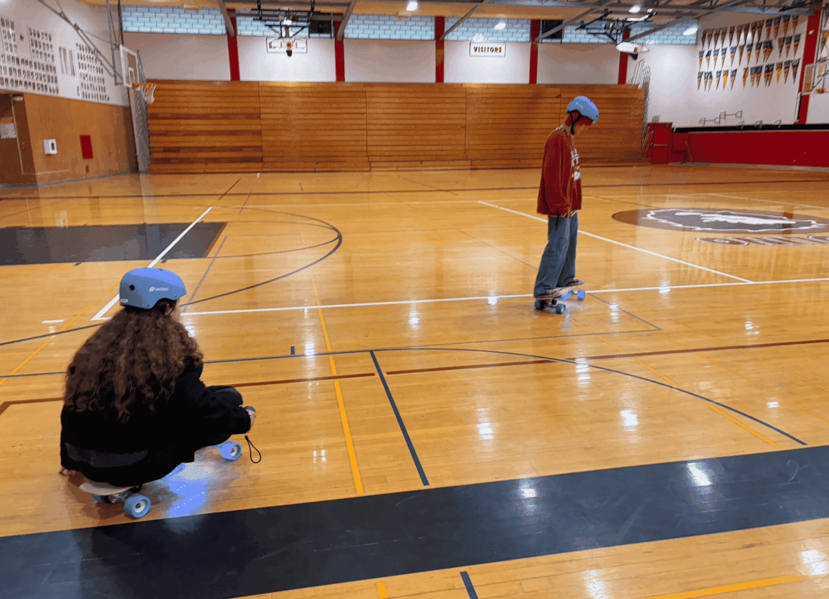 Students in helmets testing electric skateboards they built in a school gym through the STEM Kit Lending Library