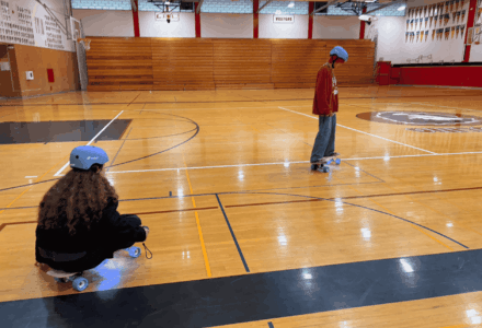 Students in helmets testing electric skateboards they built in a school gym through the STEM Kit Lending Library